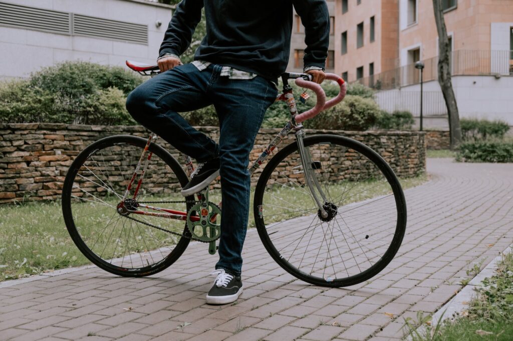 man in jeans and sneakers posing by bicycle on pavement